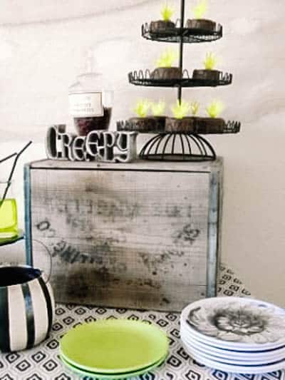 A wooden box with metal stand with baked goods and a decorative sign that says "creepy".