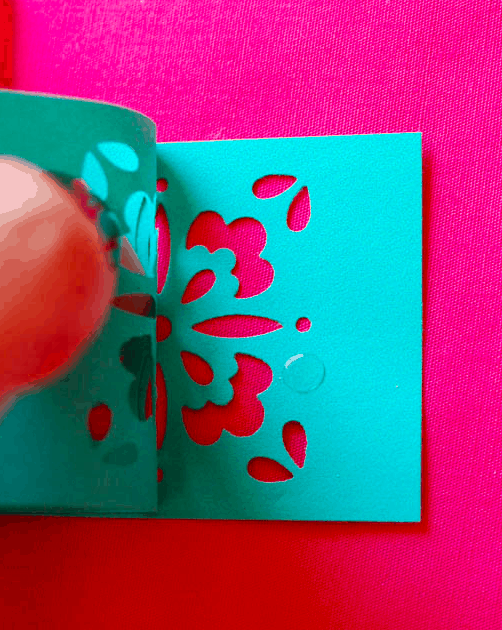 Close up of a glue dot on a piece of paper with cut-outs. 