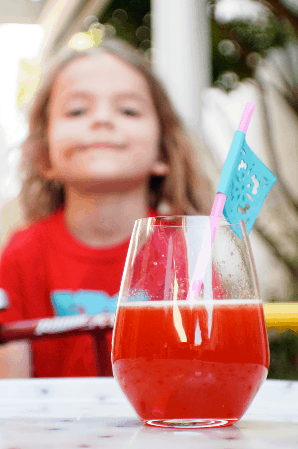 Close up of a margarita with basil and strawberry and a kid in the background.