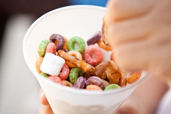 Kid eating a homemade snack mix out of a paper cone. 