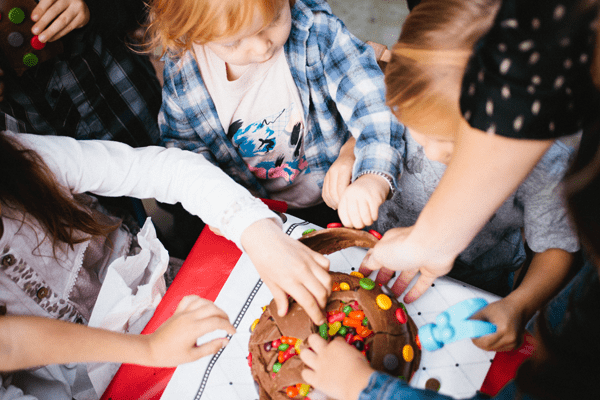 Kids reaching for a candy-filled cake. 