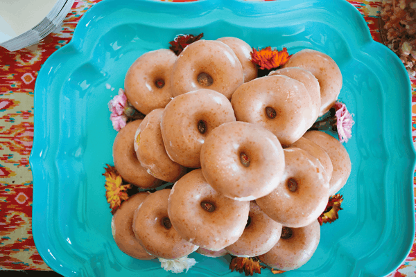 A stack of Krispie Kreme donuts on a tray with flowers. 