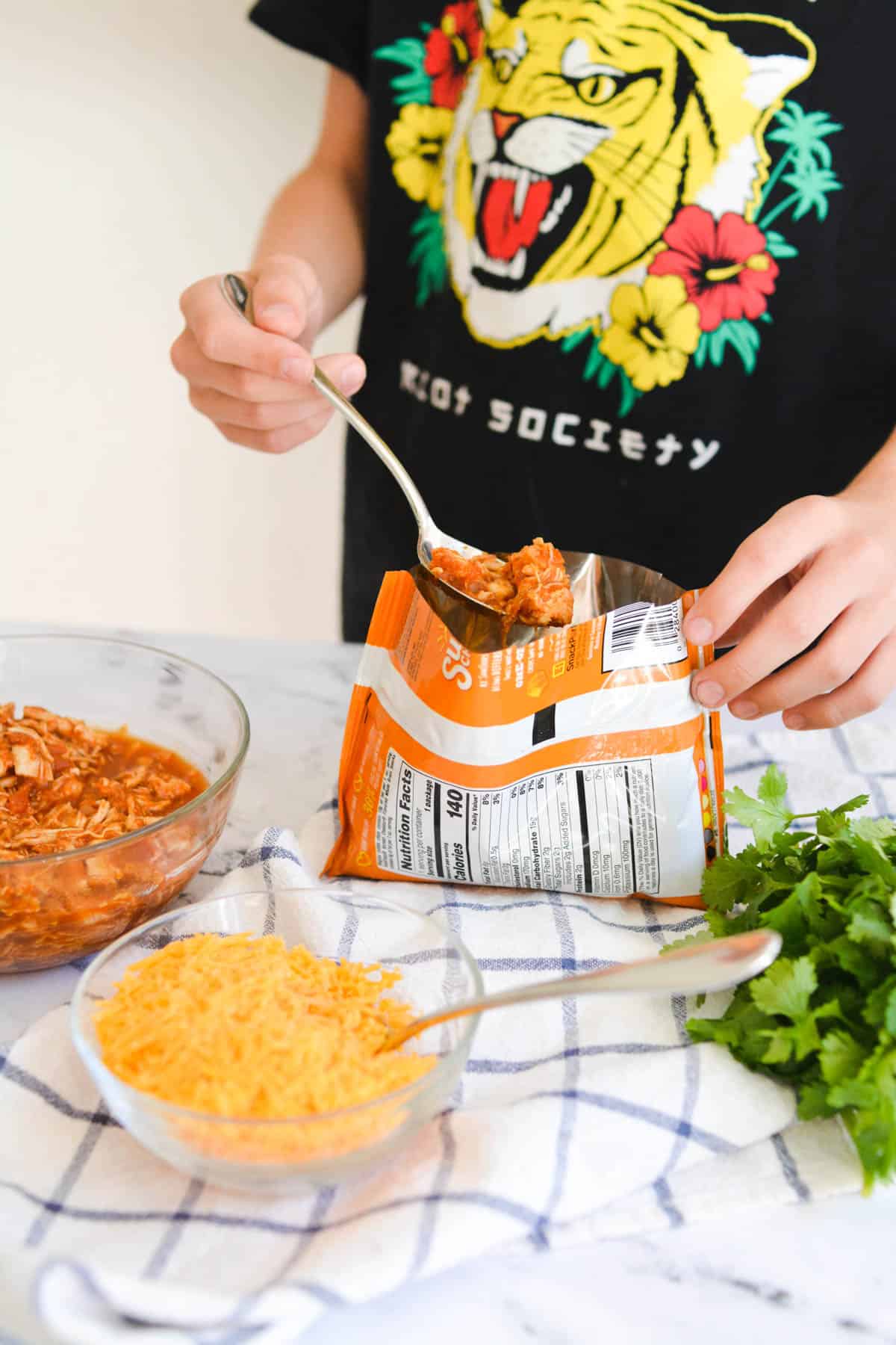 Kid adding chicken to a bag of chips for a dinner walking taco.