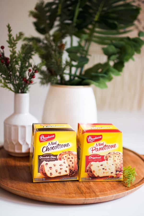 Boxed panettone varieties on a wooden tray.