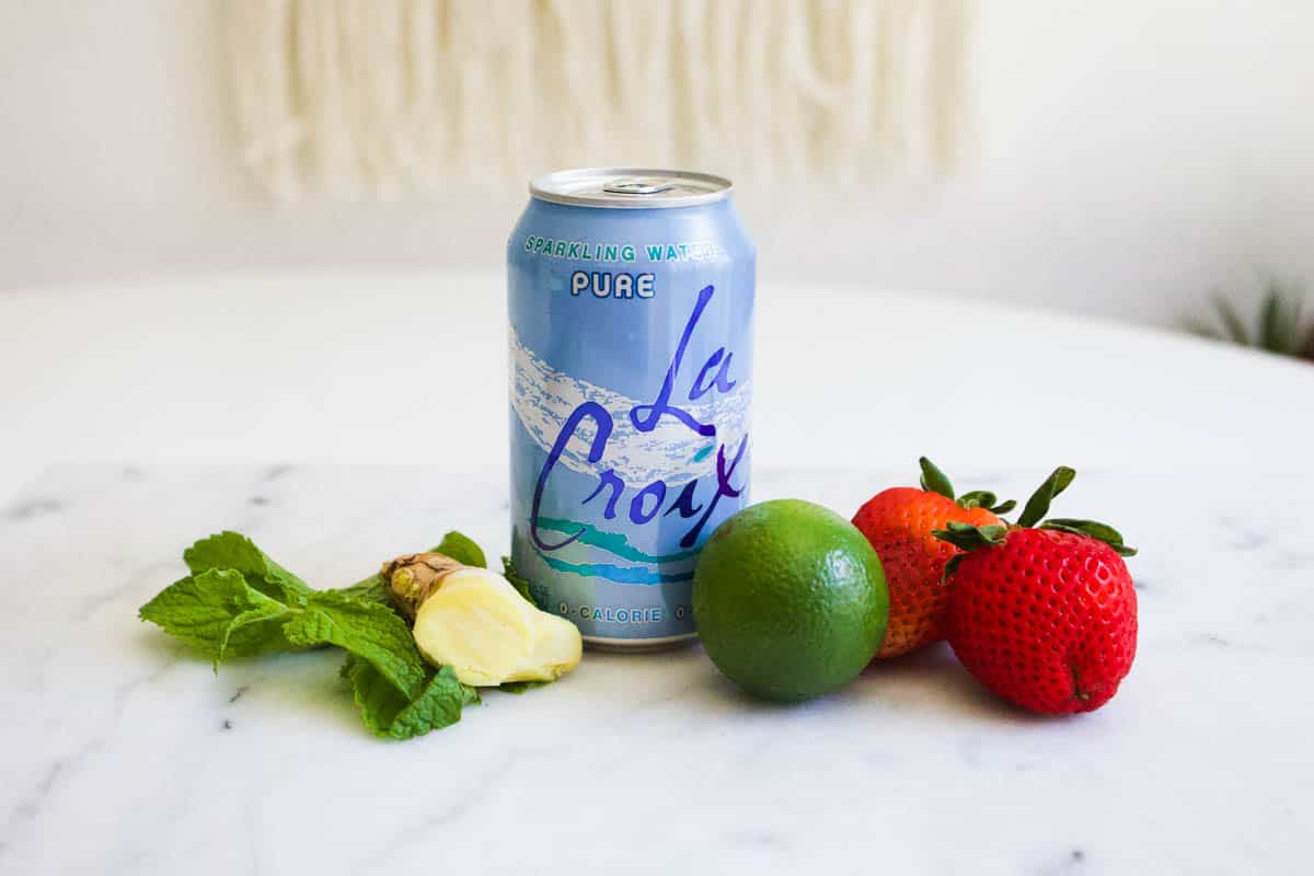 Ingredients to make a strawberry sparkling water recipe on a table.