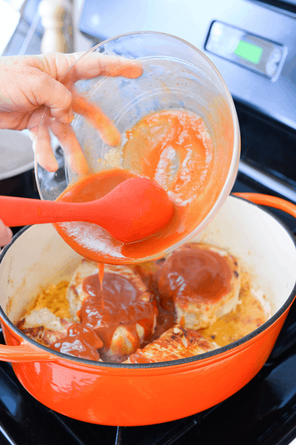 Woman scooping sauce into a post with pork chops.