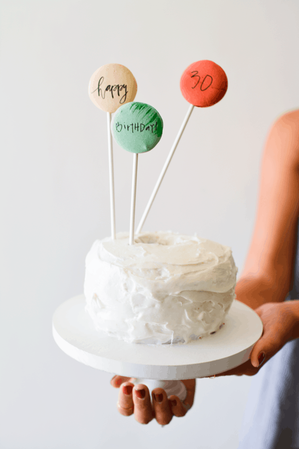 Written on macaron cookies stuck on sticks that are placed in the top of a cake.