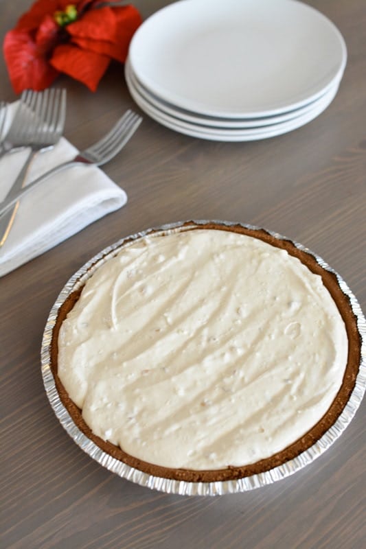 Peanut butter pie on the counter with a stack of plates and forks.