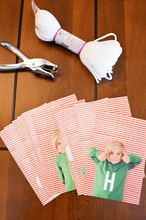 Printed photos on a table next to string and a hole punch. 