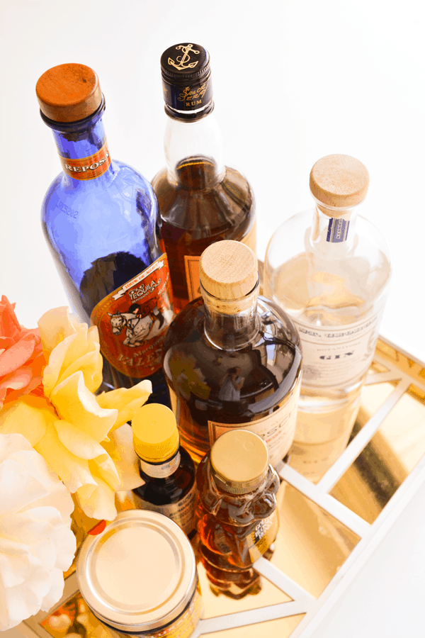 Bottles of liquor on a tray along with a bear shaped bottle of honey.