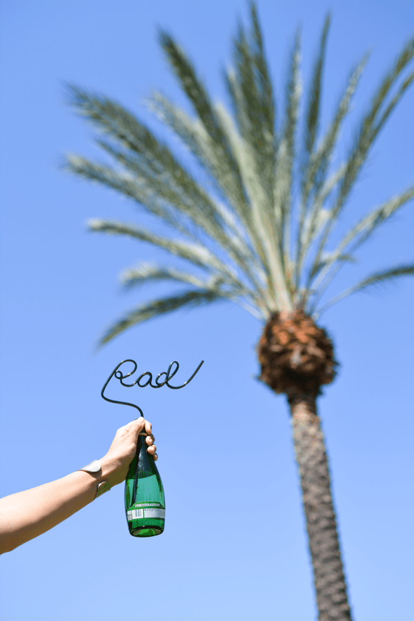 Custom crazy straws are rad like this one in a bottle next to a palm tree.