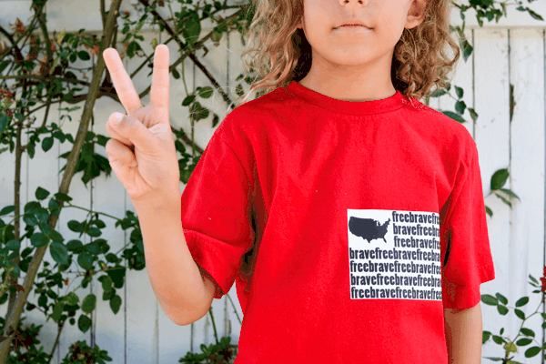 Kid with red tshirt on with an ironed on patriotic flag made of words for fourth of july. 