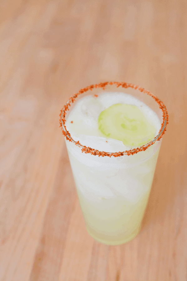 Close up of a margarita with a Tajin rim and a slice of cucumber as garnish.