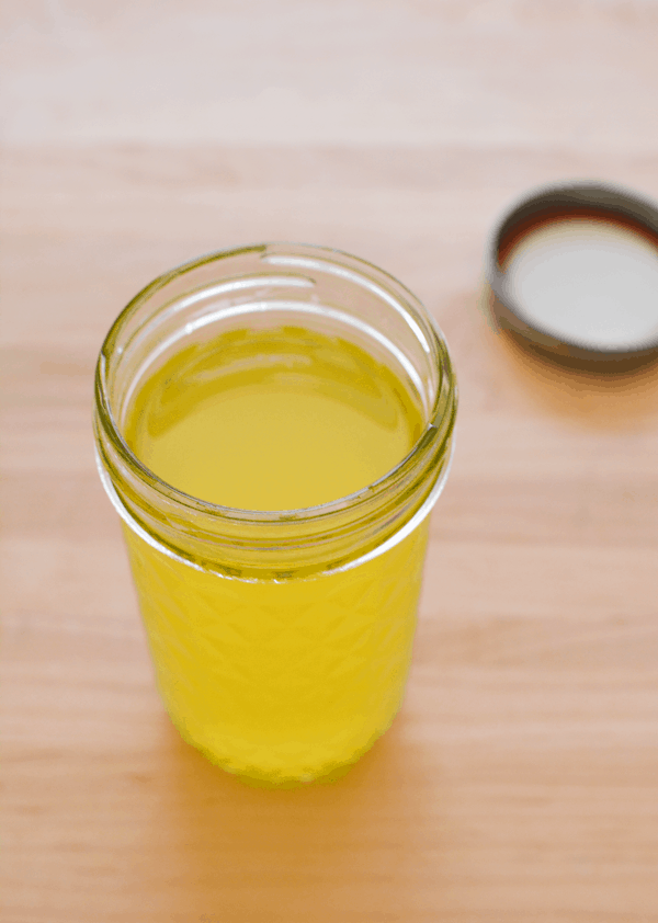 A jar on a counter top with orange infused vodka.