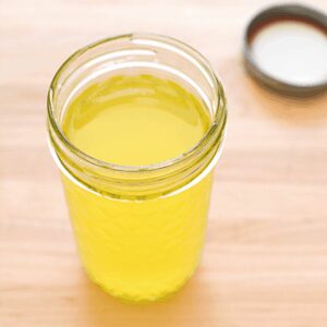 Close up of a jar holding homemade infused vodka with oranges.