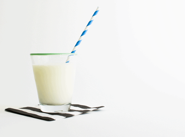 Milk in a glass with a straw in it. 