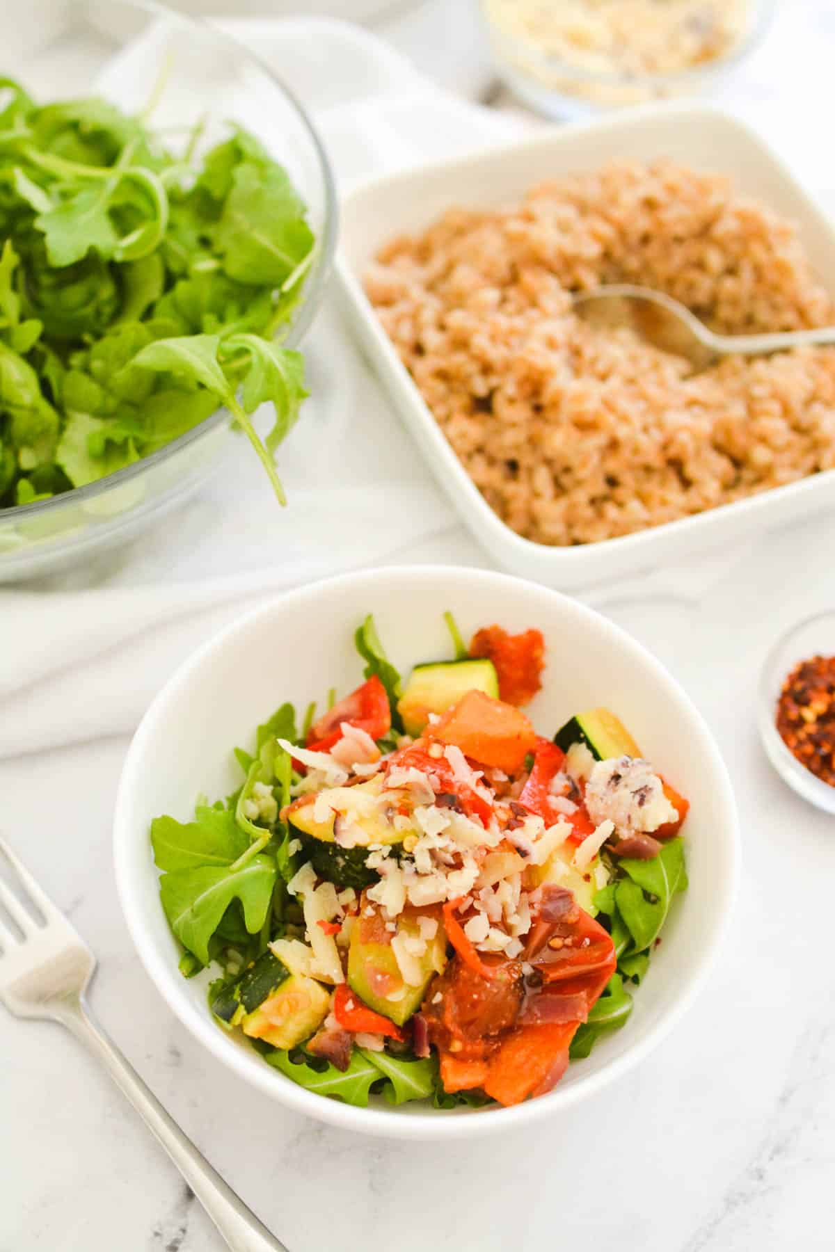 Close up of a farro arugula salad with roasted veggies.