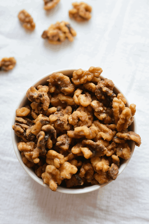 A bowl of cinnamon glazed nuts on a table with a white cloth.