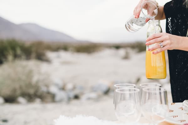 Woman holding a bottle of pineapple juice and adding club soda to it. 