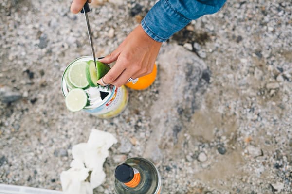 Woman slicing a lime on top of a large can of pineapple juice outside. 