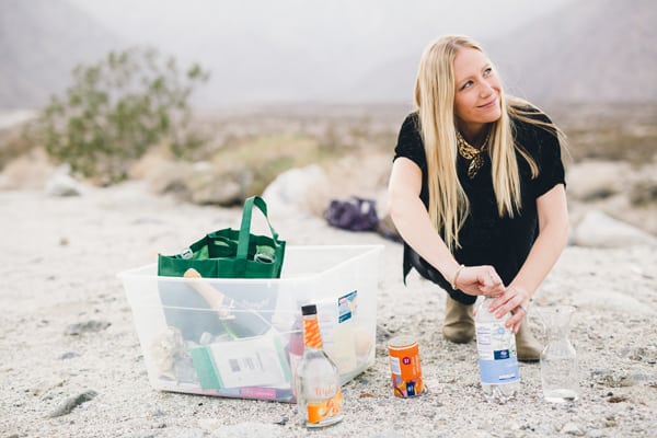 Woman outside next to a bin with recipe ingredients to make a champagne punch. 