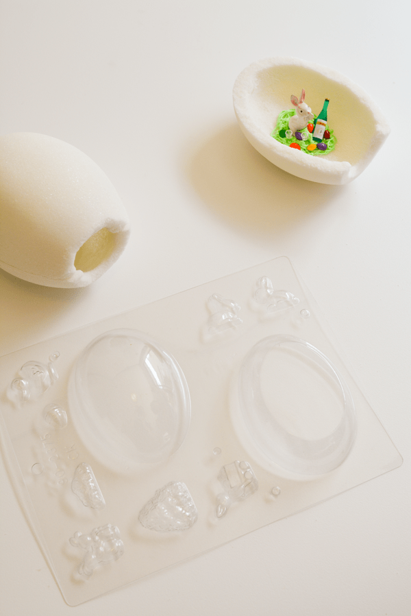 A plastic egg mold and sugar Easter eggs on a table.