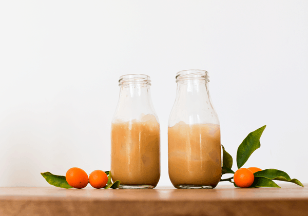 White Russian with rum instead of vodka in glass bottles on a wood board