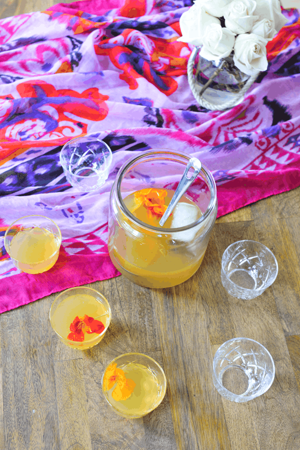 Rum punch recipe with grapefruit rum and a vanilla bean and cinnamon simple syrup in a punch bowl surrounded by glasses of punch.