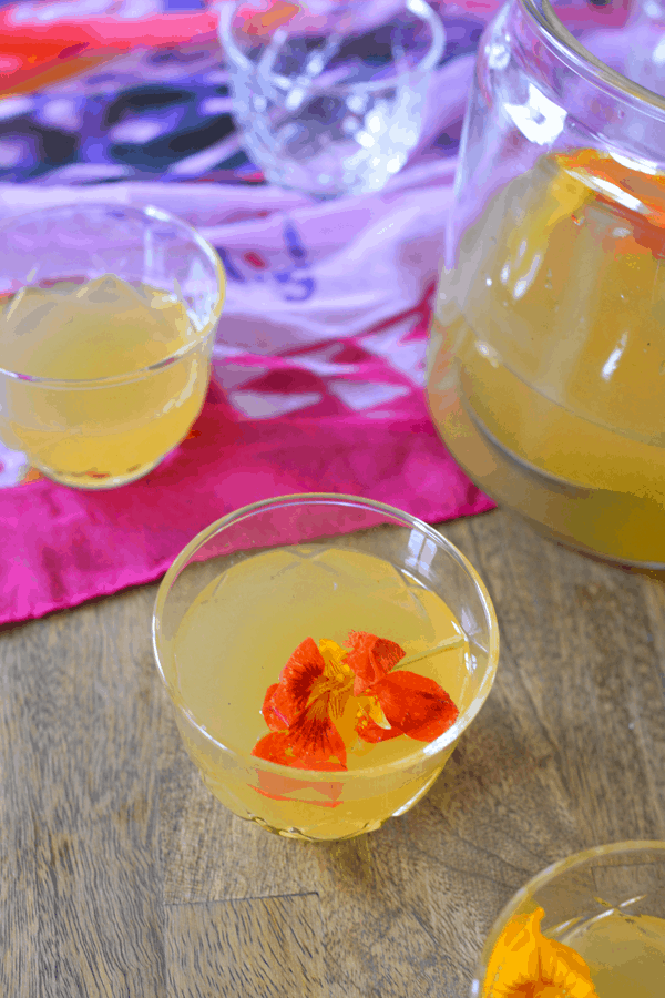 Close up image of rum punch in a small glass and topped with flowers.