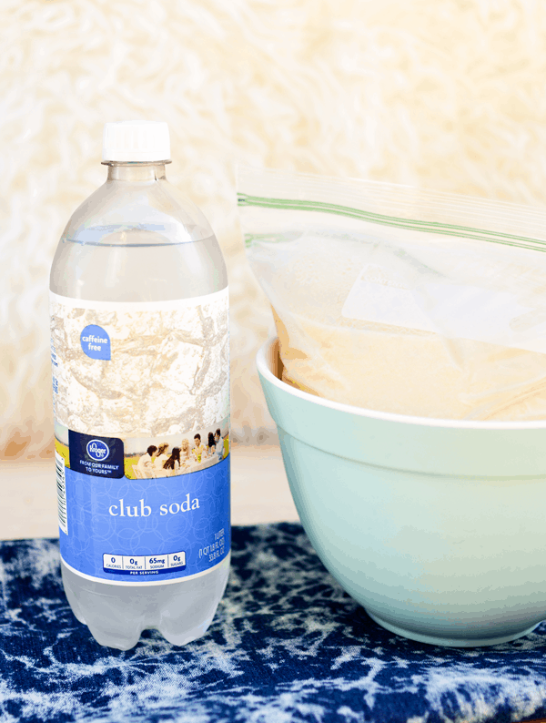 Bottle of club soda next to a bowl with a frozen Pina Colada in a freezer bag.