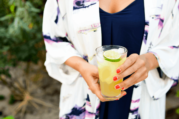 Woman holding a margarita garnished with a slice of lime.