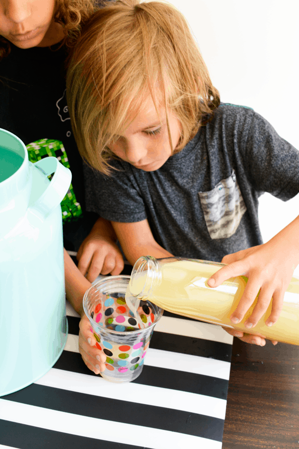 Two kids making lemonade for their lemonade stand. 