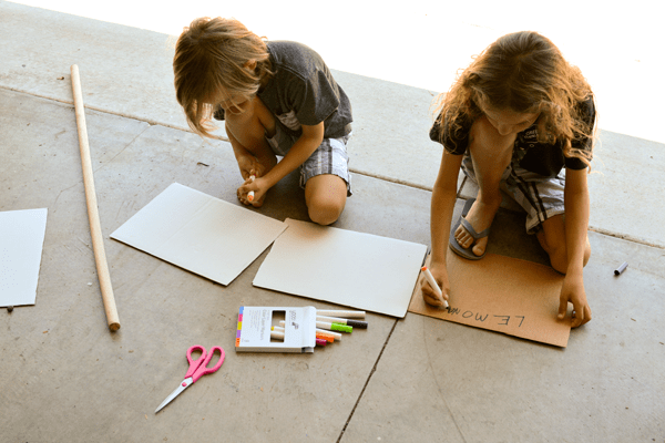 Kids making signs for their lemonade stand to raise money for charity. 