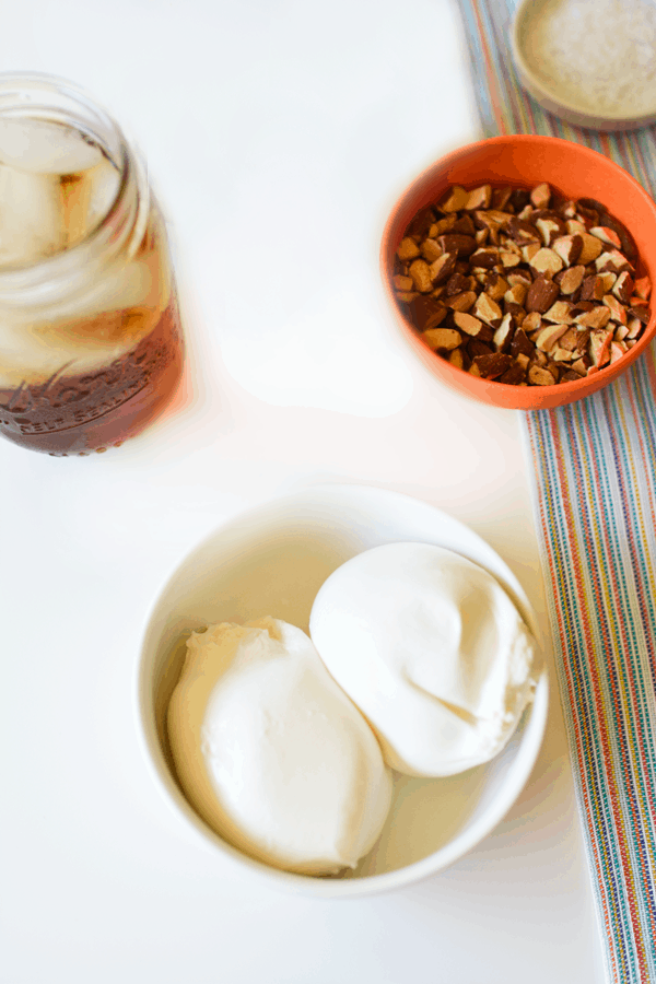 Burrata cheese in a small bowl on a table next to a bowl of almonds. 