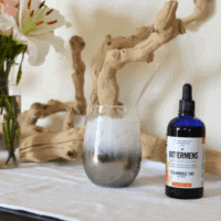 A stemless wine glass on a table with a bottle of bitters next to it.