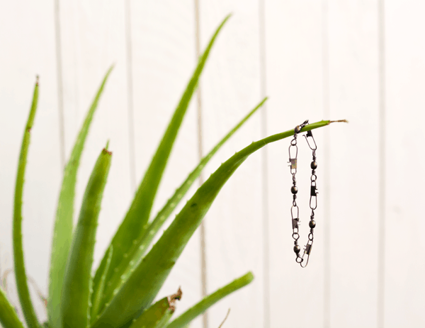 A snap swivel bracelet hanging from an aloe vera plant. 