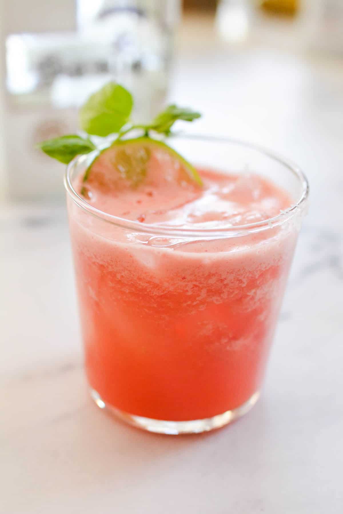 Watermelon margarita in a cocktail glass on the counter.