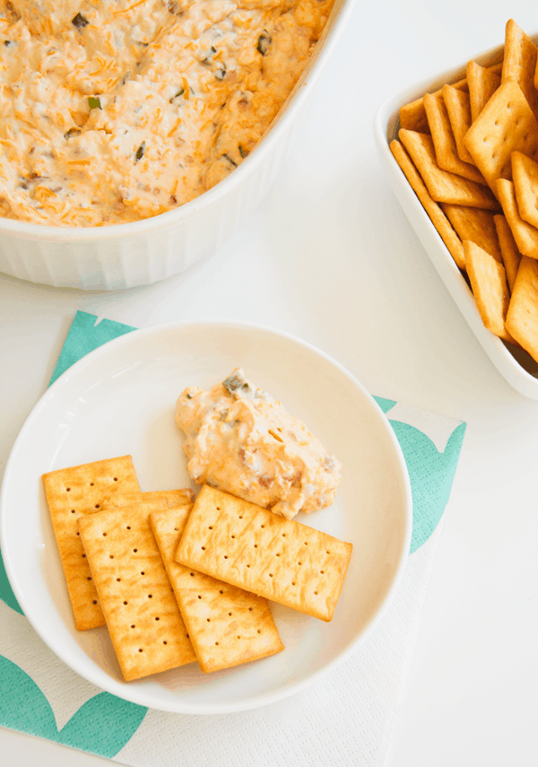 A small appetizer plate with a portion of dip on it next to some crackers. 