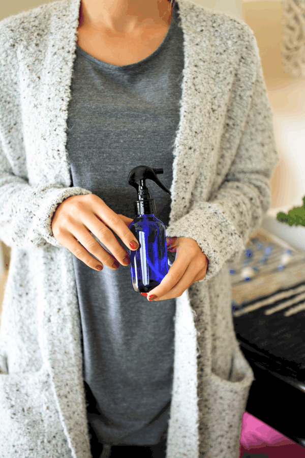 Woman holding Rosewater DIY room spray with essential oils for the home.