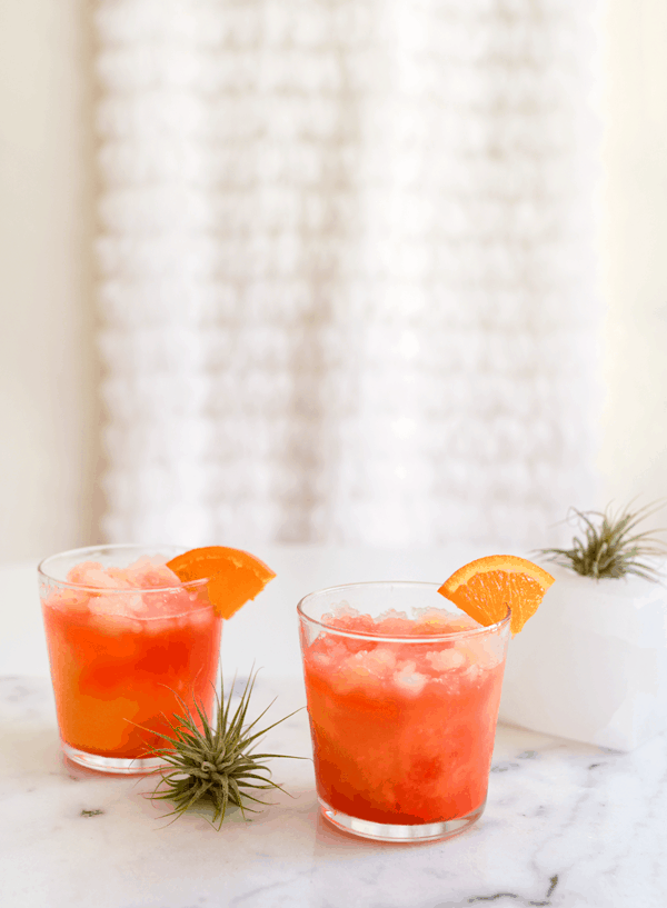 Pink and orange Vodka Sunrise cocktails in glasses on a table. 