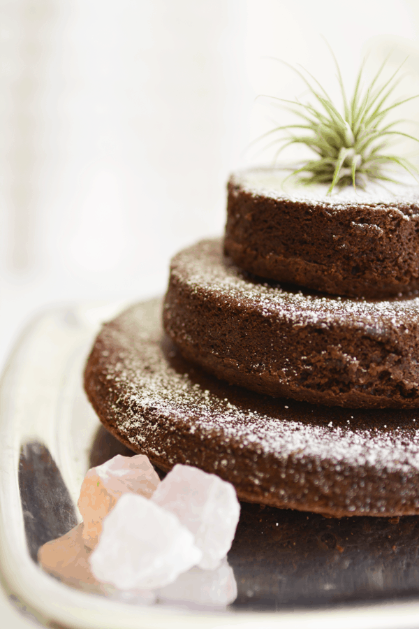 Close up image of a three tiered brownie cake on a silver cake plate.