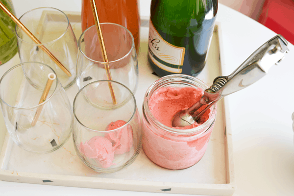 Ingredients to make a champagne sorbet cocktail including sorbet, champagne and strawberry lemonade.