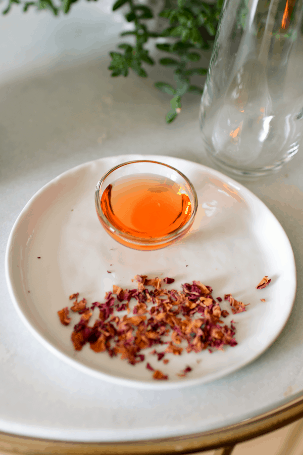 A small plate with chopped dried rose petals next to a small bowl of rose syrup. 