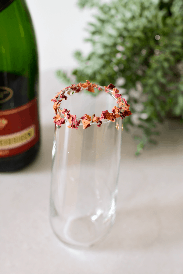 Close up of a champagne flute with a rim made from dried rose petals. 