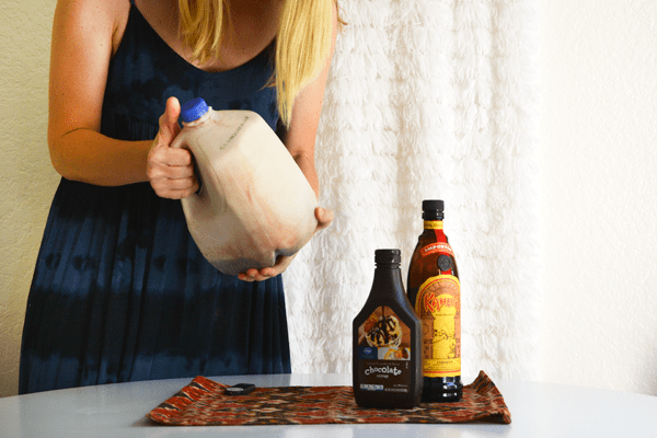 Woman shaking the milk jug full of milk, Kahlua, and chocolate syrup.