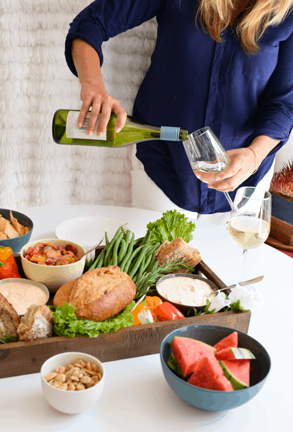 Woman pouring a glass of wine for a party. 