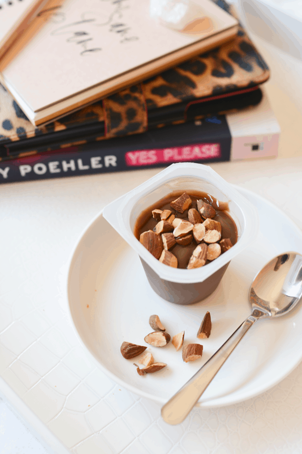 Close up of a chocolate pudding cup with chopped almonds on top. 