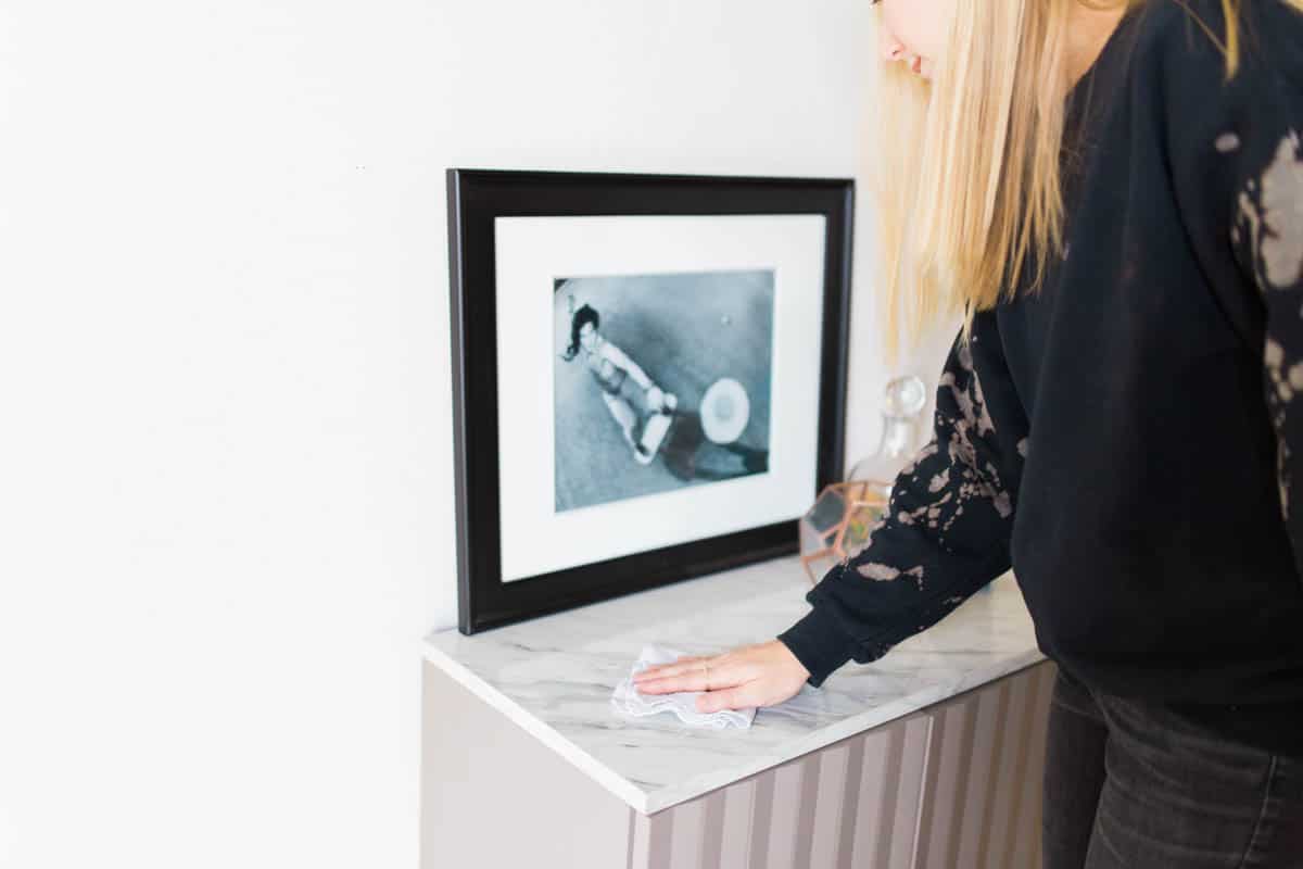 Woman using a rag to clean a small piece of furniture.