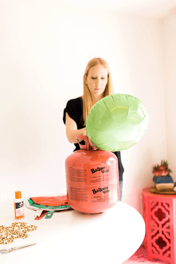 Woman blowing up a helium balloon with a tank. 