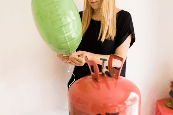 Woman adding ribbon to a balloon she blew up with helium.